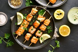 Crispy salmon bites cooked in an air fryer, garnished with sesame seeds and green onions on a white plate