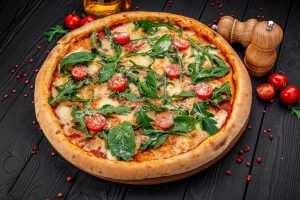 Healthy homemade white pizza topped with turkey sausage, red peppers, onions, and arugula on a whole wheat crust