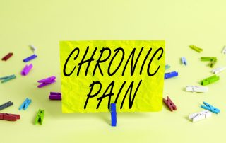 Chronic pain sign with colorful clothespins and yellow background, emphasizing awareness and management of chronic pain conditions.