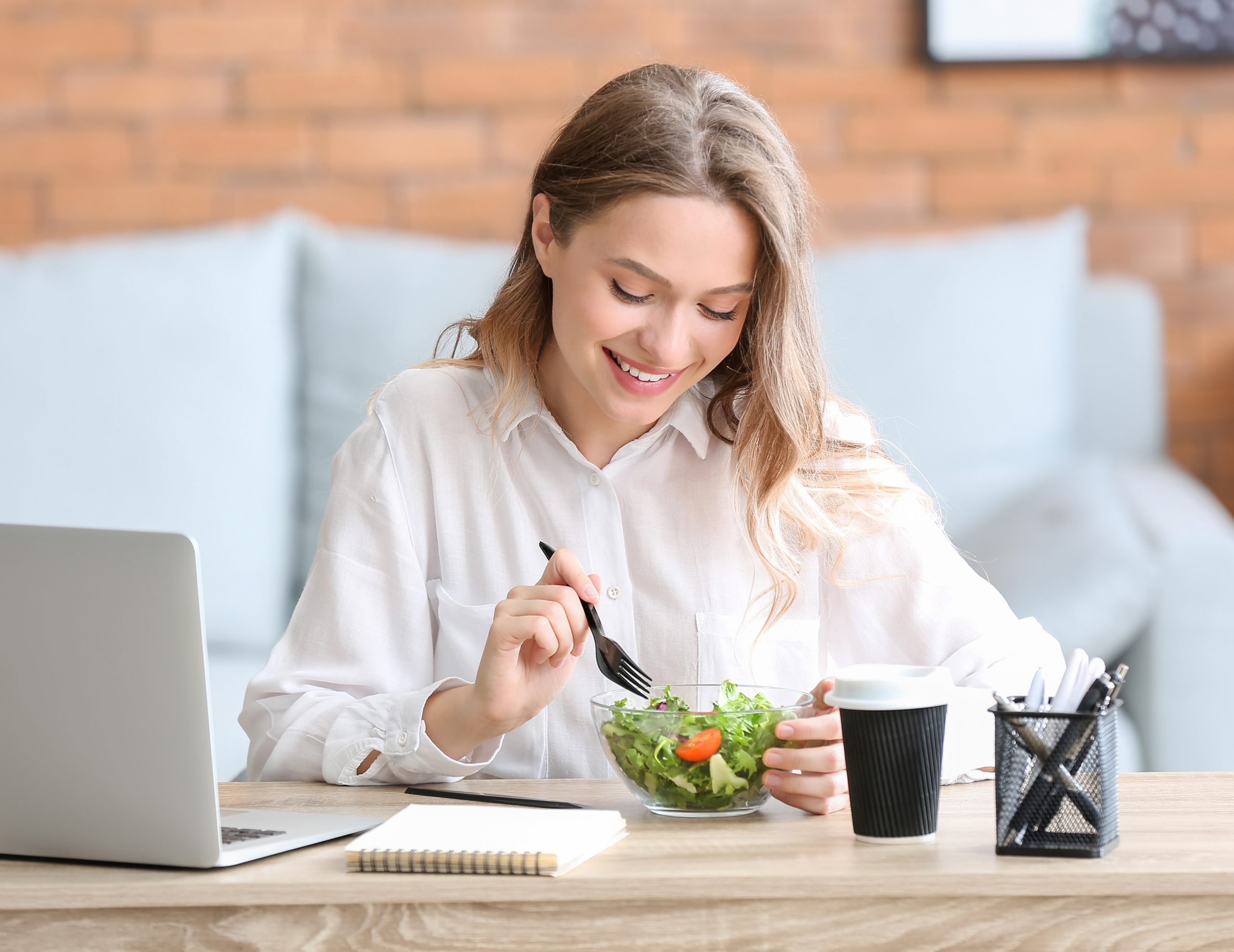 Woman eating healthy vegetable salad in office
