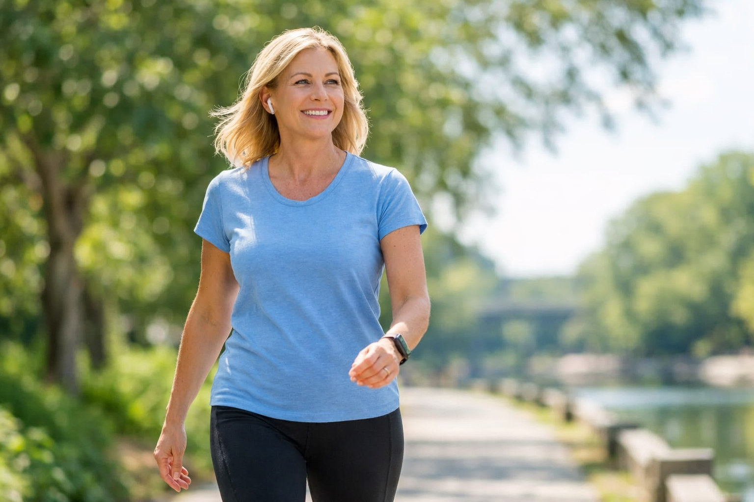 Midlife woman walking outdoors on a sunny path, representing gentle post-meal movement to support blood sugar balance, energy, and metabolic health.